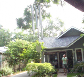 Chuck Bolotin exiting the house and walking towards the wind chime