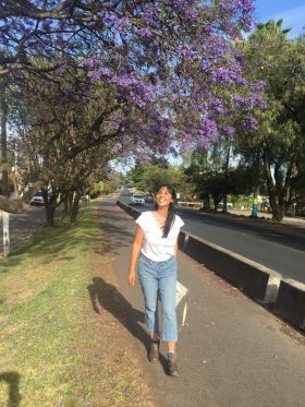 Jet Metier walking down the street in Mexico with purple flowers